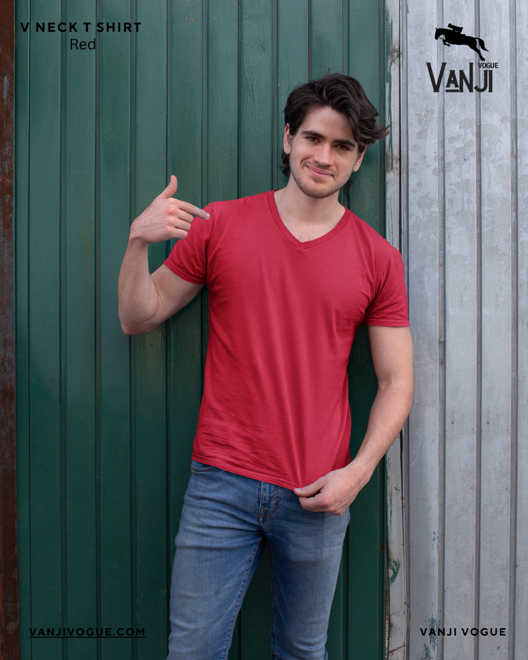 Man wearing red v neck t shirt men styled casually with blue jeans standing against green and gray wall