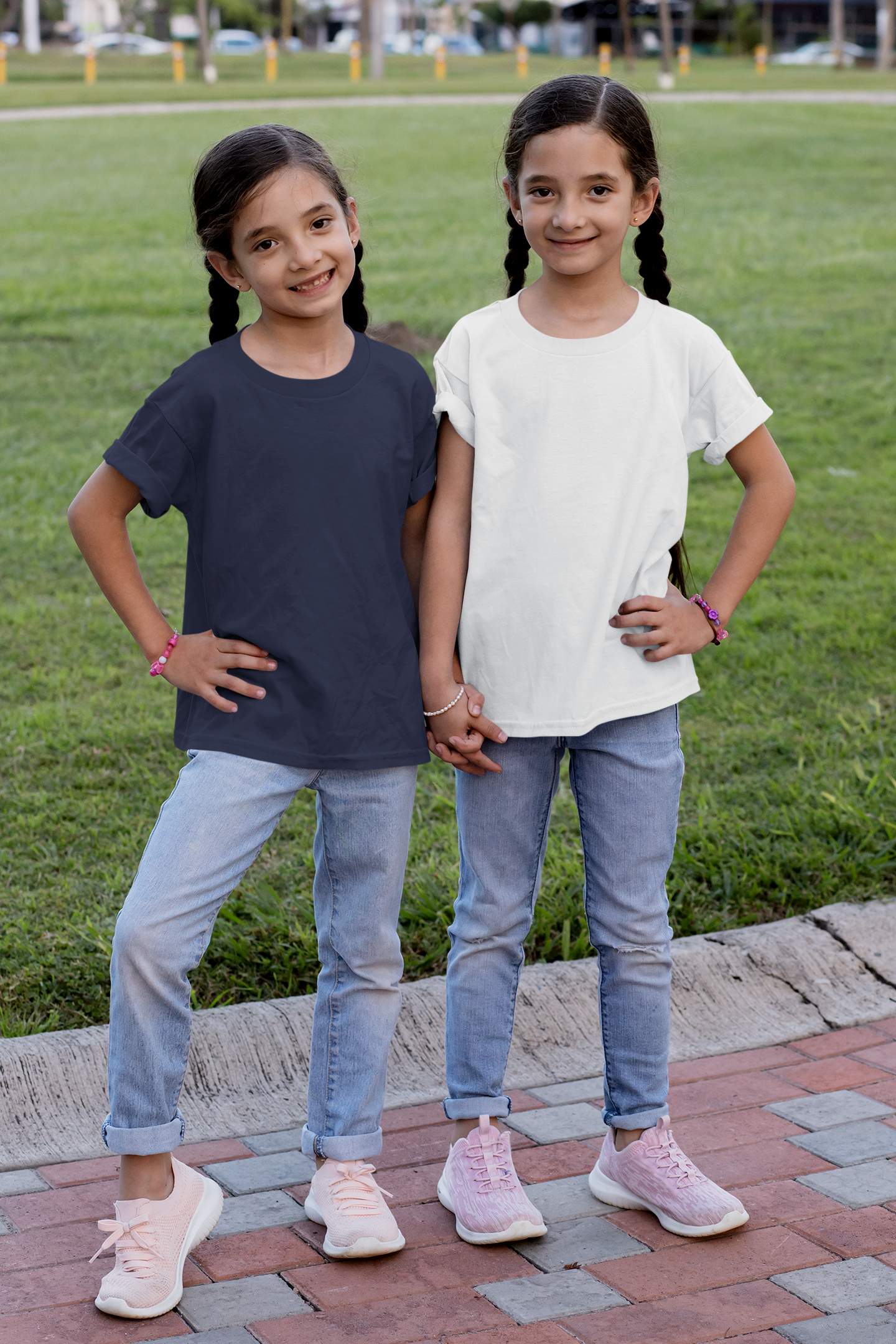 Two young girls wearing girls crew neck t-shirt in white and navy blue paired with light blue jeans outdoors