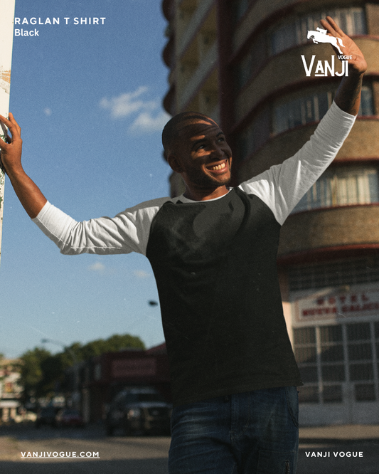 Black and white premium raglan t shirt worn by smiling man outdoors in urban setting