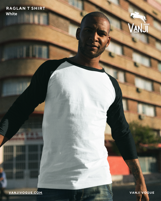 Man wearing a white and black premium raglan t shirt standing outdoors in front of a building